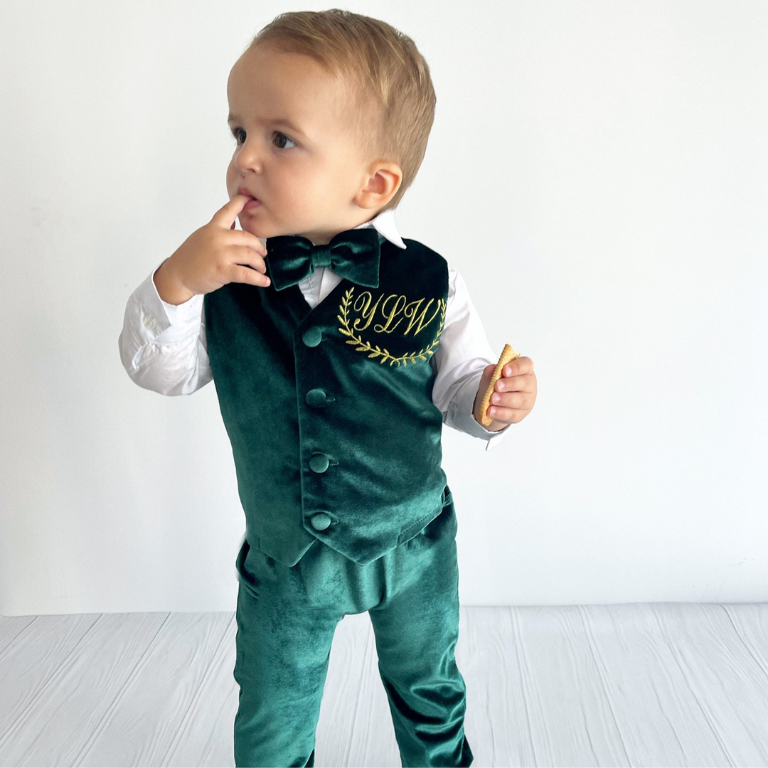 Child wearing a green velvet suit with a white shirt and bow tie on a white background