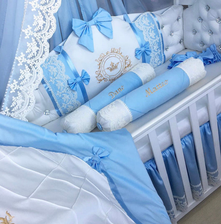Baby crib with blue and white bedding set, including pillows and a canopy.