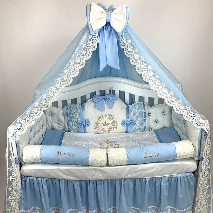 Baby crib with blue and white bedding, including a canopy and decorative pillows.