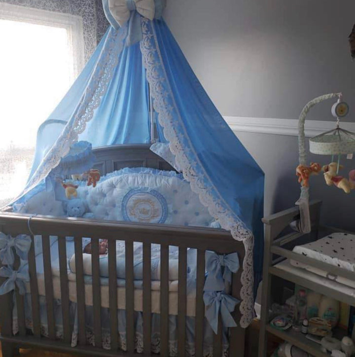 Baby crib with blue canopy and bedding in a nursery setting.