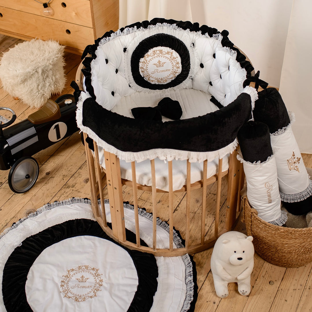 Baby crib with black and white bedding, surrounded by toys on a wooden floor.