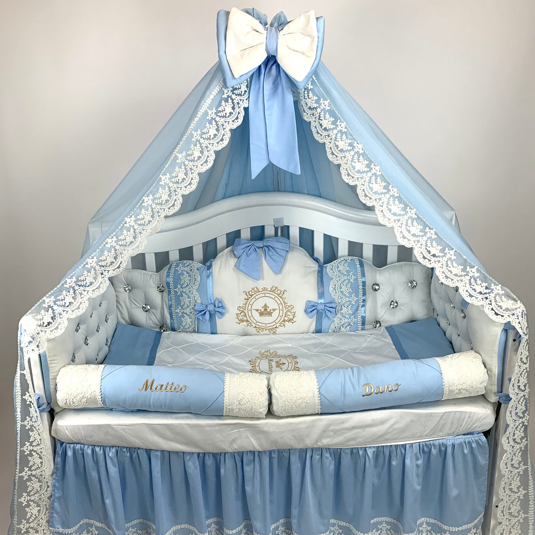 Baby crib with blue and white bedding, including a canopy and decorative pillows.
