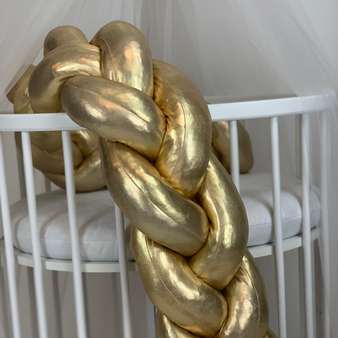 Gold braided decorative item in front of a white crib