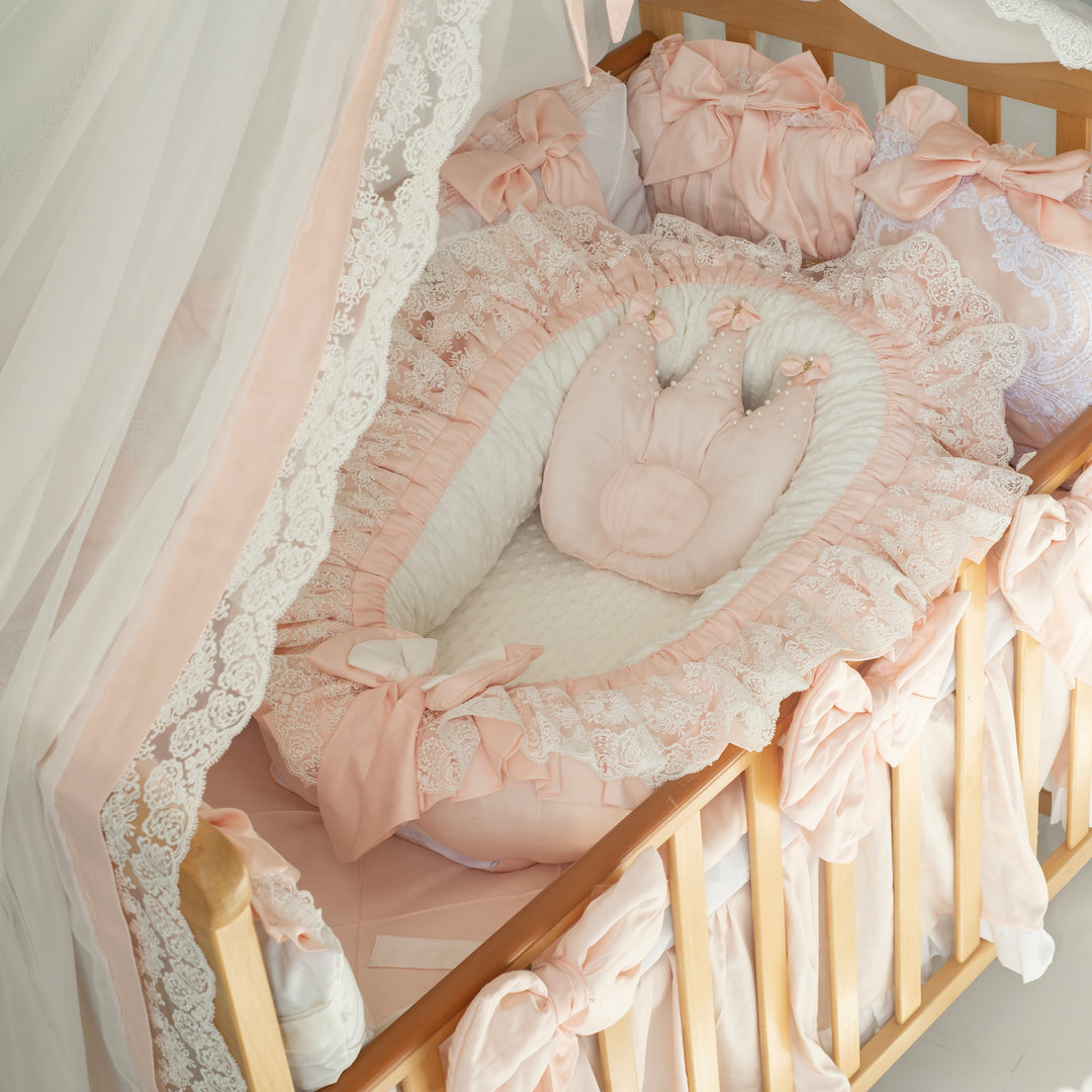Delicate pink crib set with lace details in a baby crib.