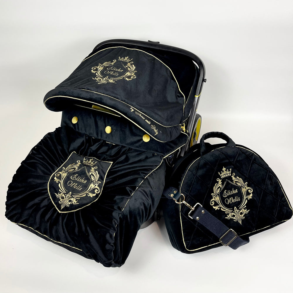 Black baby car seat with gold embroidery on a white background