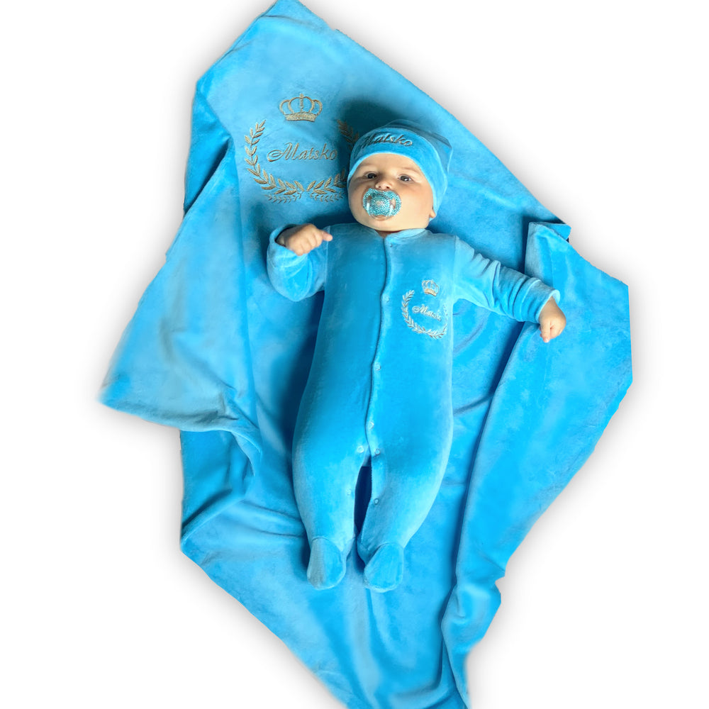 Baby in blue outfit and blanket with 'Royal Baby' text on a white background