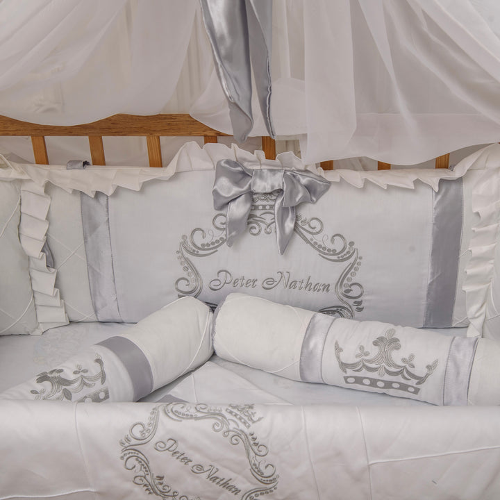 White crib set with gray embroidery and 'Peter Nathan' branding, featuring a canopy.