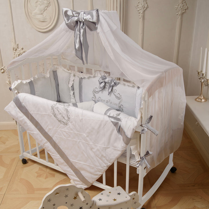 Baby crib with white and gray bedding in a decorated room