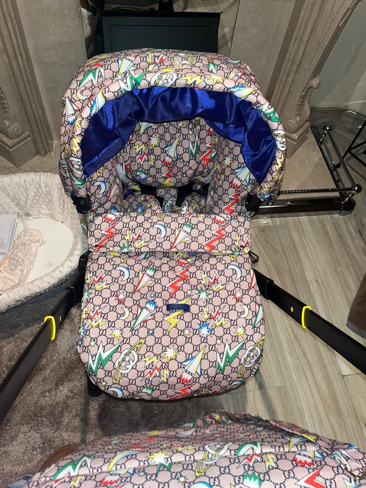 Monogram print Doona+ car seat cover with colorful lightning design and blue satin canopy lining, installed on Doona+ stroller, front interior lifestyle view.