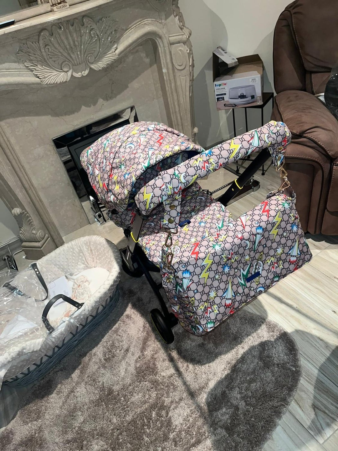 Monogram print Doona+ car seat cover set with colorful lightning design, matching diaper bag, footmuff and handlebar cover, installed on Doona+ stroller in home interior setting.