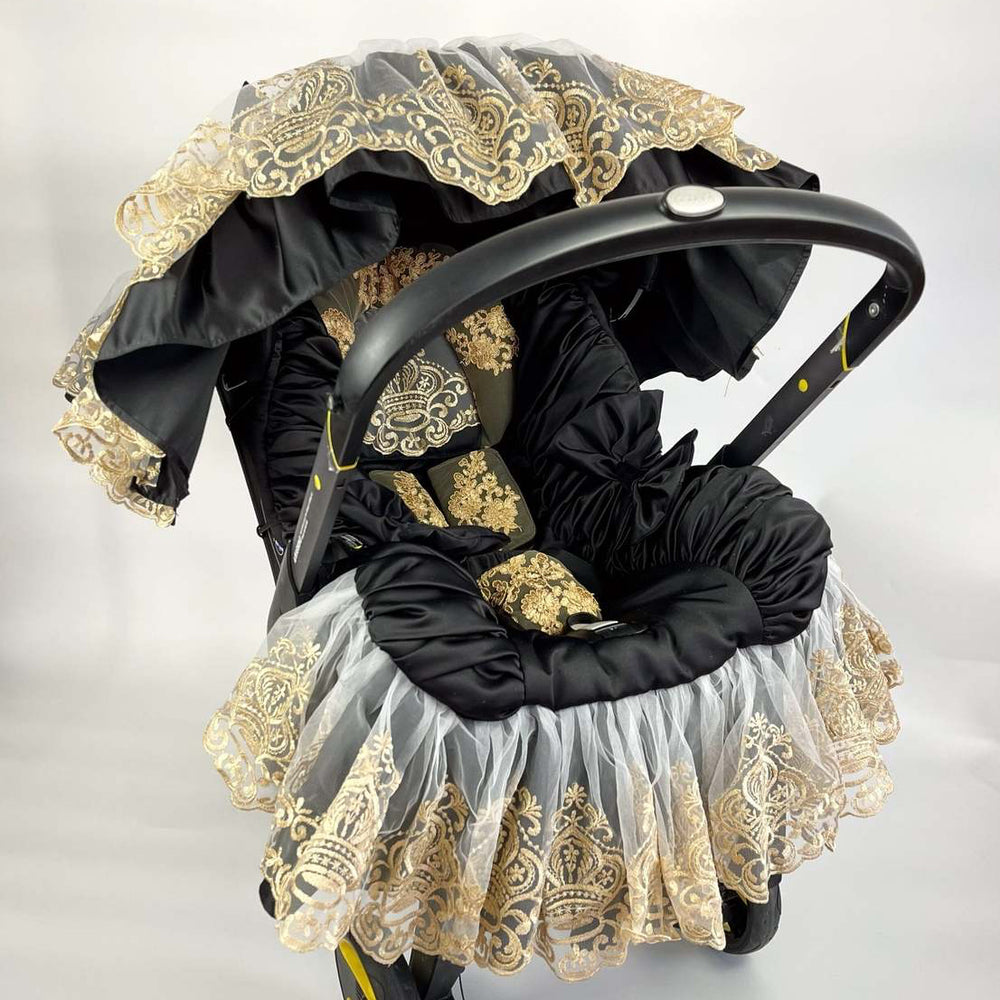 Decorative baby car seat cover with black and gold lace on a white background