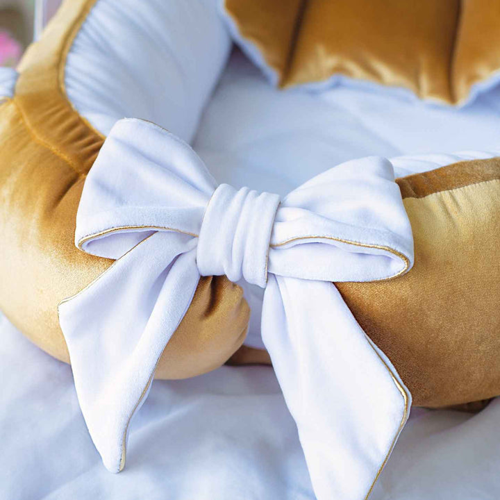 Gold cushion with a white bow on a light blue background