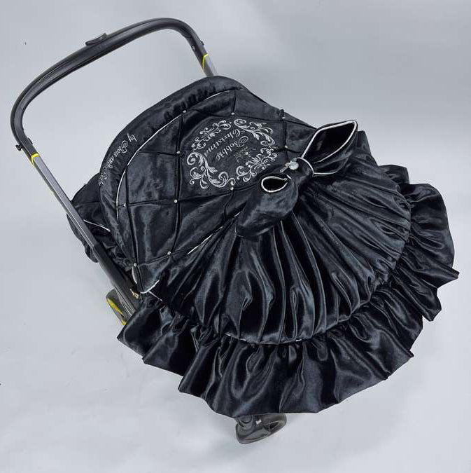 Top view of a luxury black velvet quilted stroller canopy featuring ‘By Boss & Baby’ embroidery, personalized name embroidery, decorative bow with rhinestones and dramatic ruffle detailing.