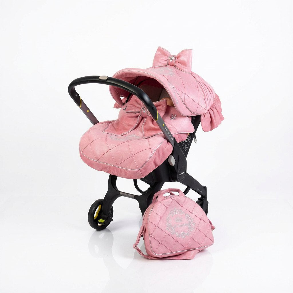 Sparkly pink baby car seat cover set with rhinestones, quilted fabric, decorative bows, matching hood, footmuff, and diaper bag. 