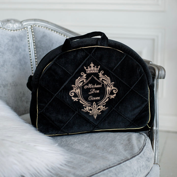 Black quilted bag with gold embroidery on a gray chair