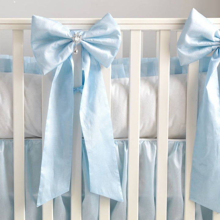 Crib with light blue ribbons and bows on a white background