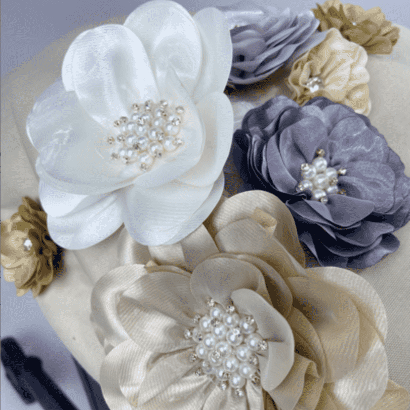 Close-up of beige Doona car seat canopy with handmade 3D fabric flowers in ivory, blush, lavender and gold.