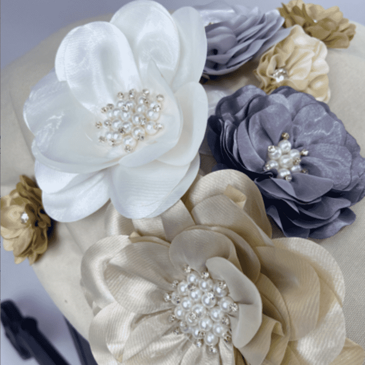 Close-up of beige Doona car seat canopy with handmade 3D fabric flowers in ivory, blush, lavender and gold.