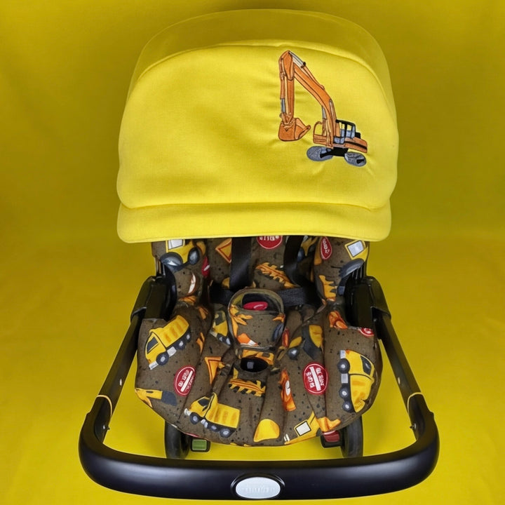 Child's stroller with yellow canopy featuring an excavator design on a yellow background
