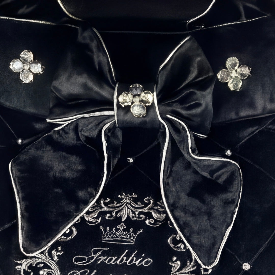 Close-up of a luxury velvet stroller cover featuring a decorative bow with crystal embellishments and personalized embroidery.