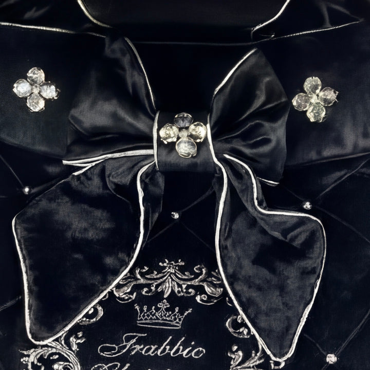 Close-up of a luxury velvet stroller cover featuring a decorative bow with crystal embellishments and personalized embroidery.
