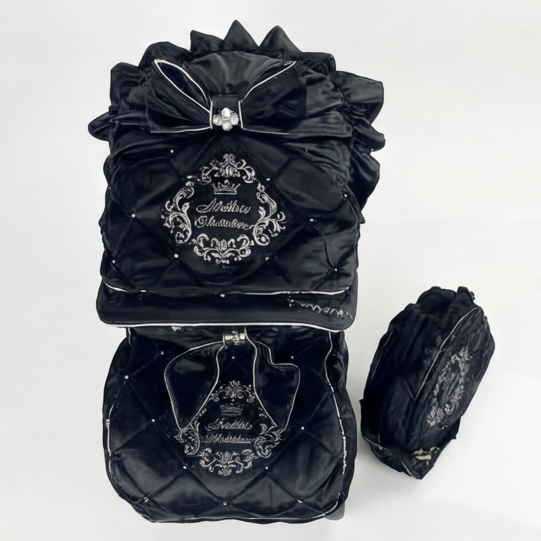 Top view of a luxury quilted velour stroller set featuring an embroidered canopy with bow, rhinestones and ruffle details, matching footmuff and diaper bag.