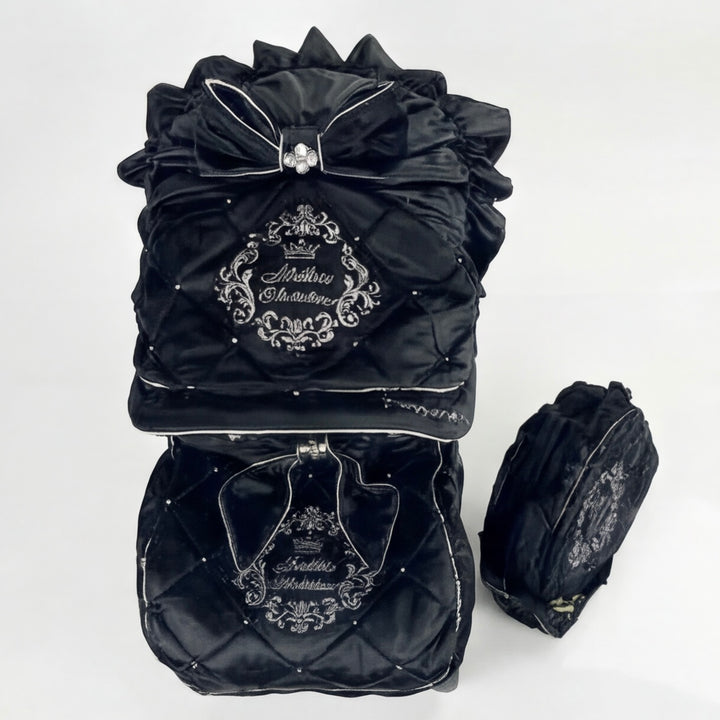 Top view of a luxury quilted velour stroller set featuring an embroidered canopy with bow, rhinestones and ruffle details, matching footmuff and diaper bag.
