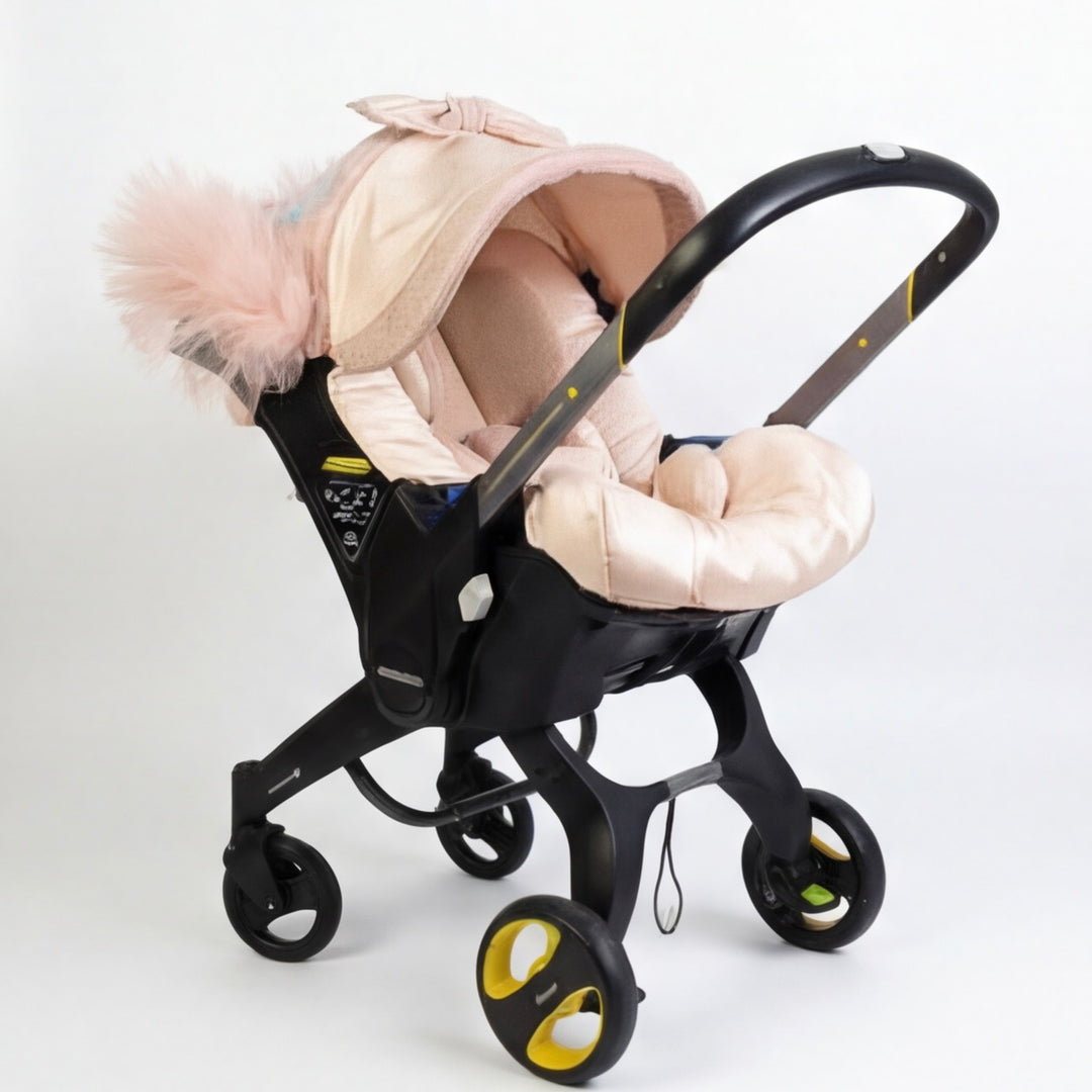 Baby car seat cover set installed on a car seat, shown at a side angle on a white background. The design features a soft blush beige color palette with a padded canopy and matching seat cover. The canopy is accented with a large airy tulle bow detail, creating an elegant and delicate look.