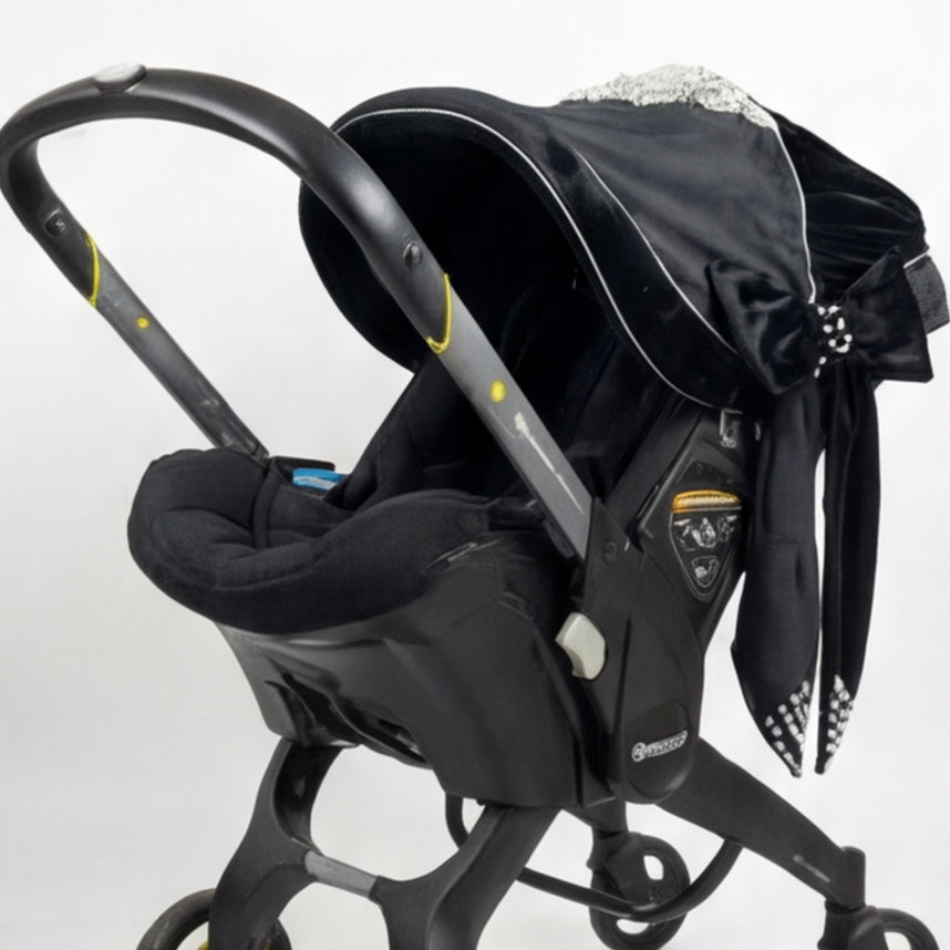 Black baby car seat with decorative bow on a white background