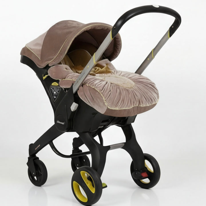 Dusty rose velvet baby car seat cover set installed on stroller frame with wheels, front three-quarter view on white background.