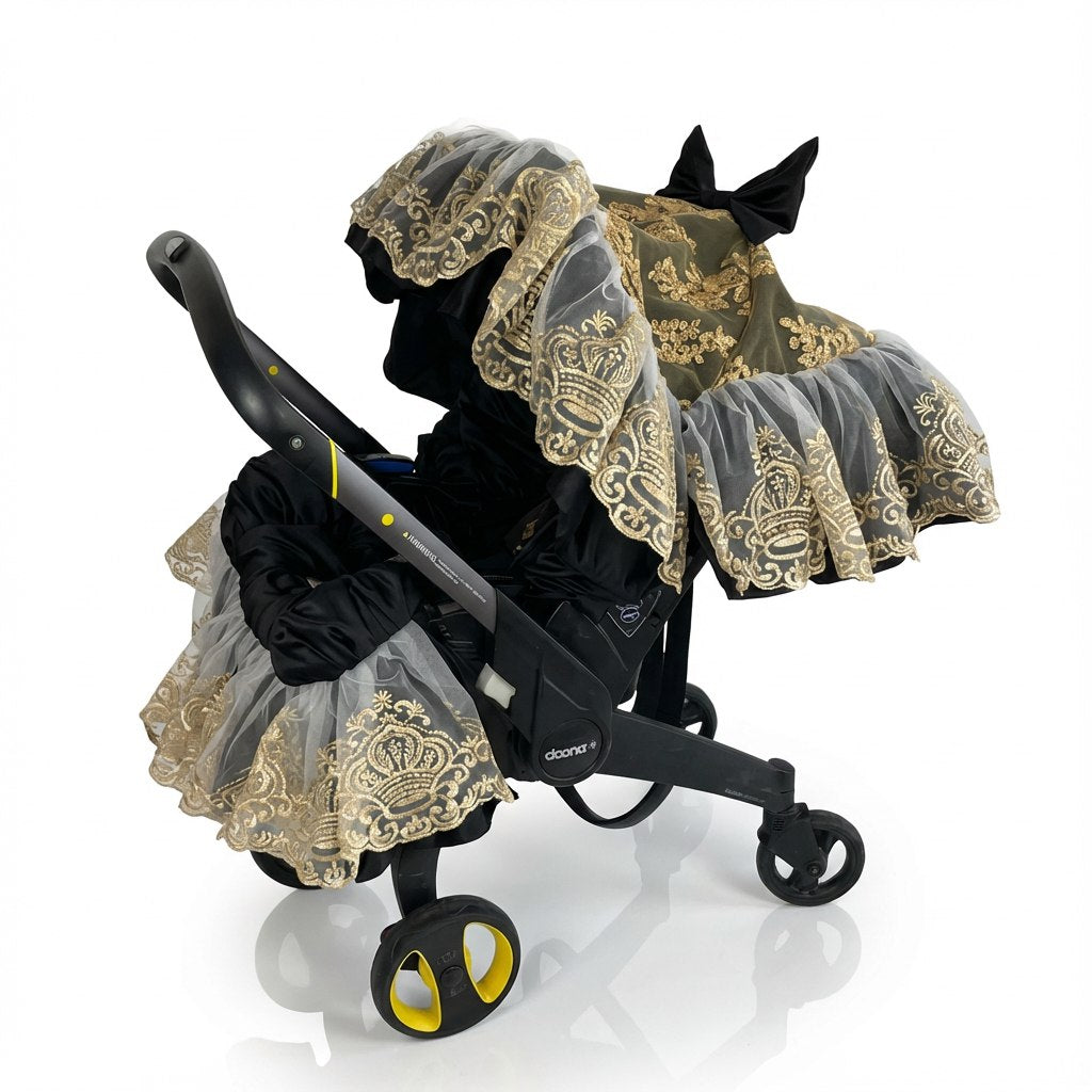 Infant car seat cover made of shimmering black satin with layered gold lace overlay and ruffled lace trim, paired with a black satin canopy accented with gold lace and a decorative bow, displayed on an infant car seat frame against a white background.
