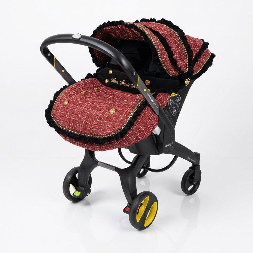 Doona+ red tweed car seat cover set with black ruffle trim and gold accents, side view.