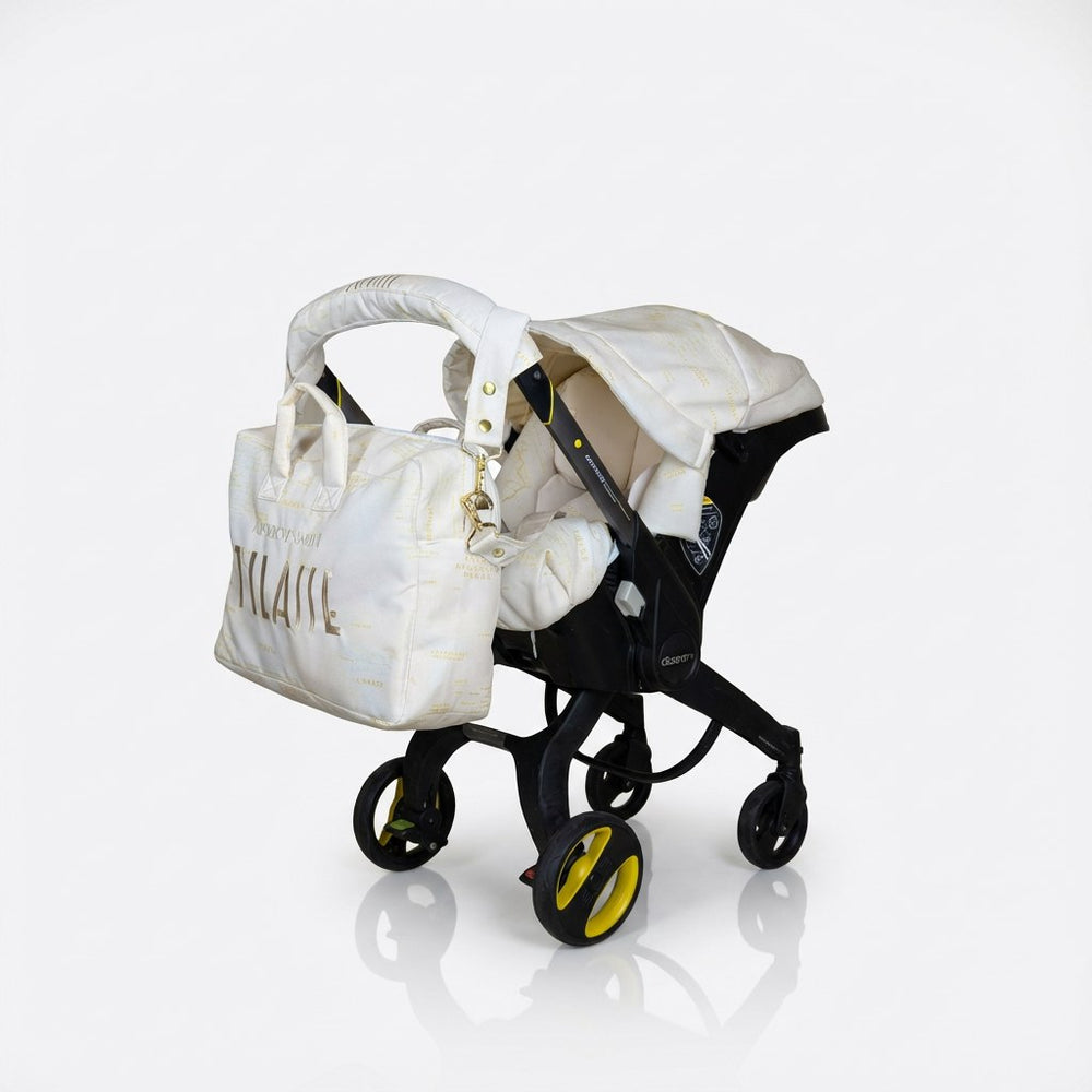 Elegant beige and gold baby car seat cover set with a world map print, padded interior, and a matching diaper bag with gold embroidery, installed on a Doona car seat and photographed on a white background.