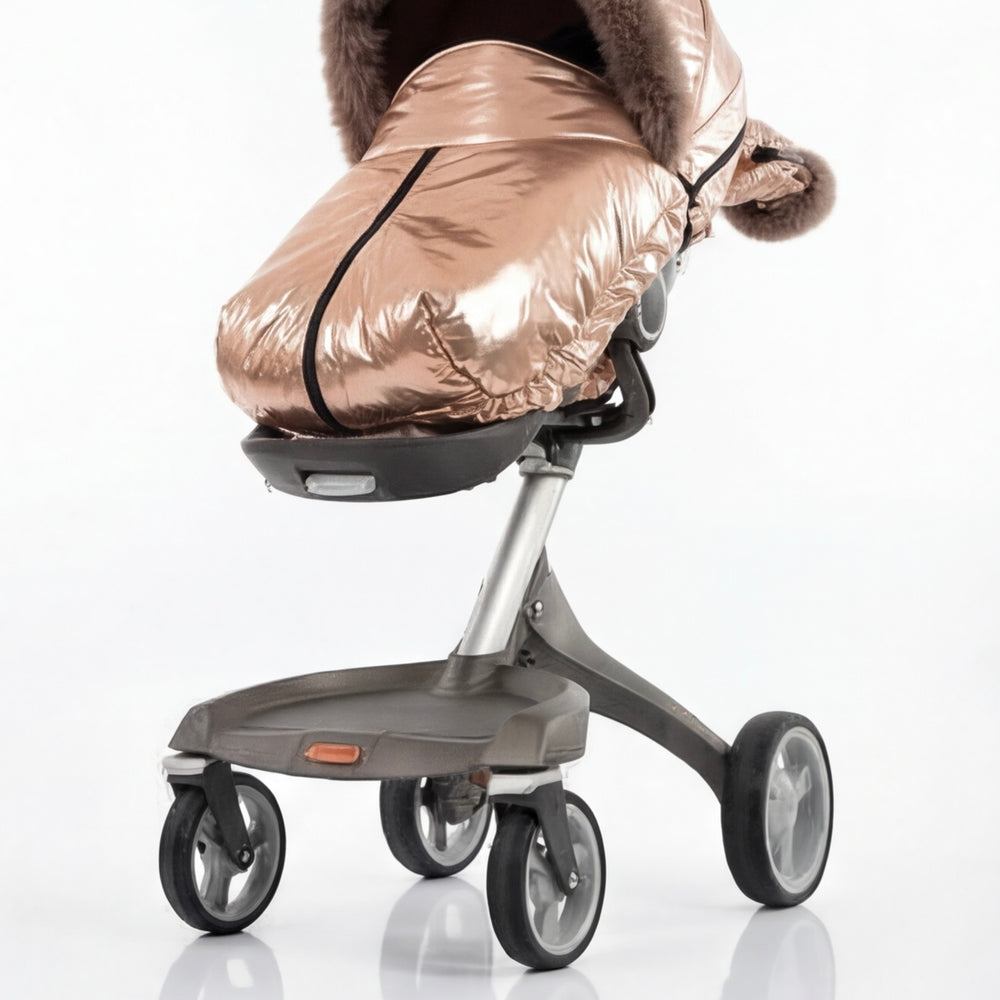 Back view of a rose gold metallic stroller cover footmuff with arctic fox fur trim, displayed on a stroller frame against a white background.