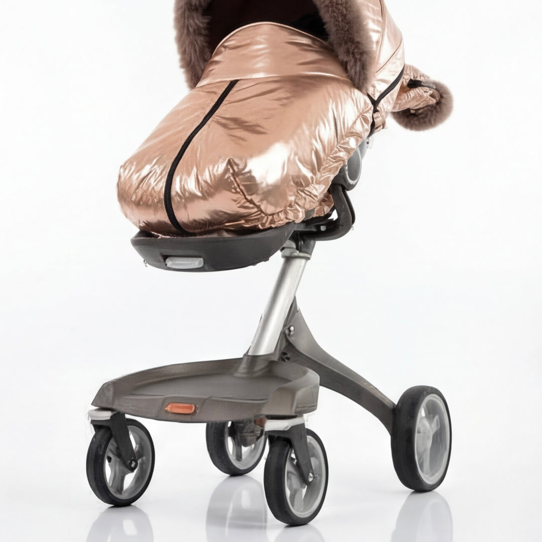 Back view of a rose gold metallic stroller cover footmuff with arctic fox fur trim, displayed on a stroller frame against a white background.