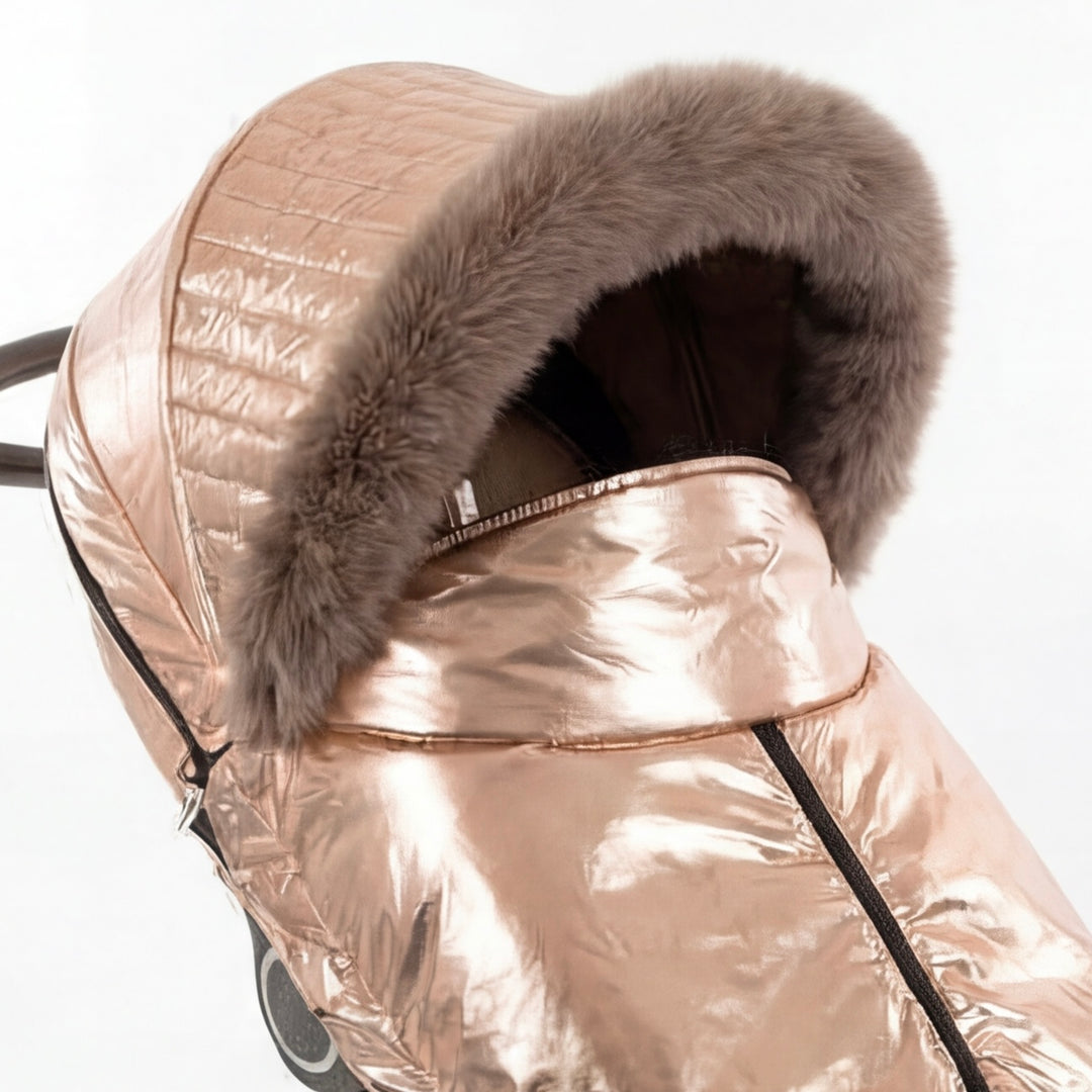 Close-up of a rose gold metallic stroller cover canopy trimmed with arctic fox fur, shown against a white background.