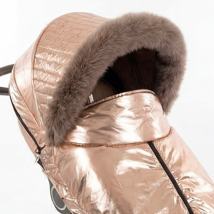 Close-up of a rose gold metallic stroller cover canopy trimmed with arctic fox fur, shown against a white background.