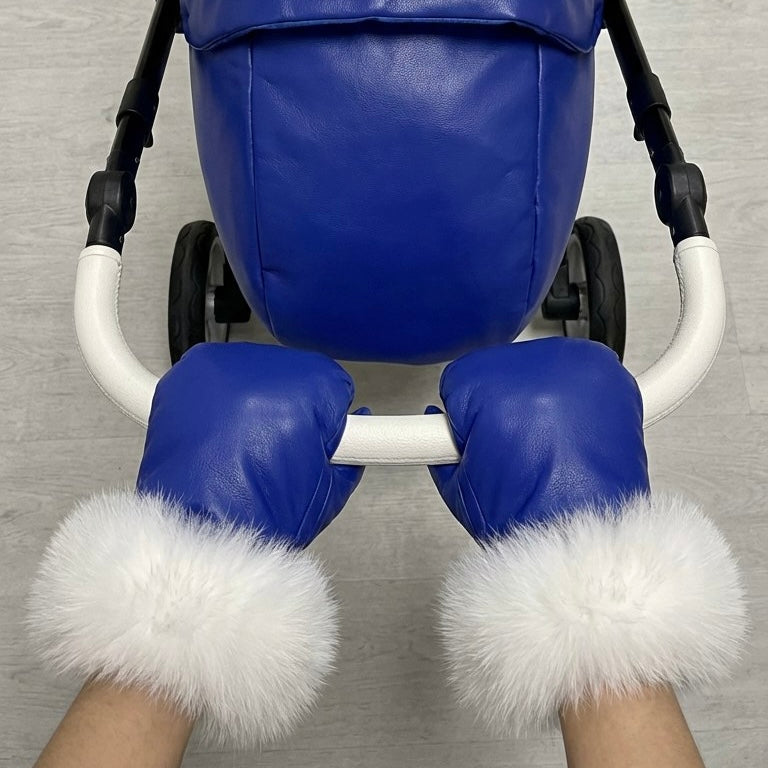Front view of blue stroller cover mittens with white arctic fox fur lining, attached to a stroller handle against a white background.