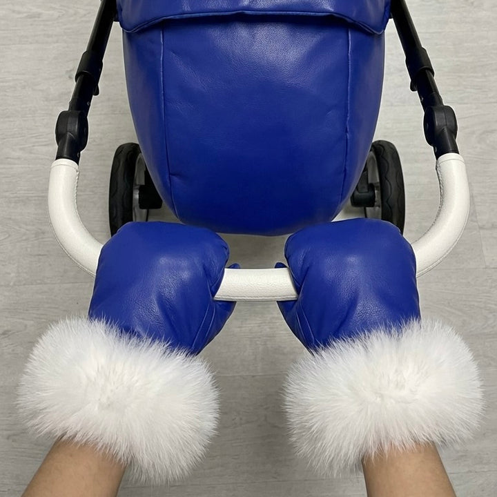 Front view of blue stroller cover mittens with white arctic fox fur lining, attached to a stroller handle against a white background.