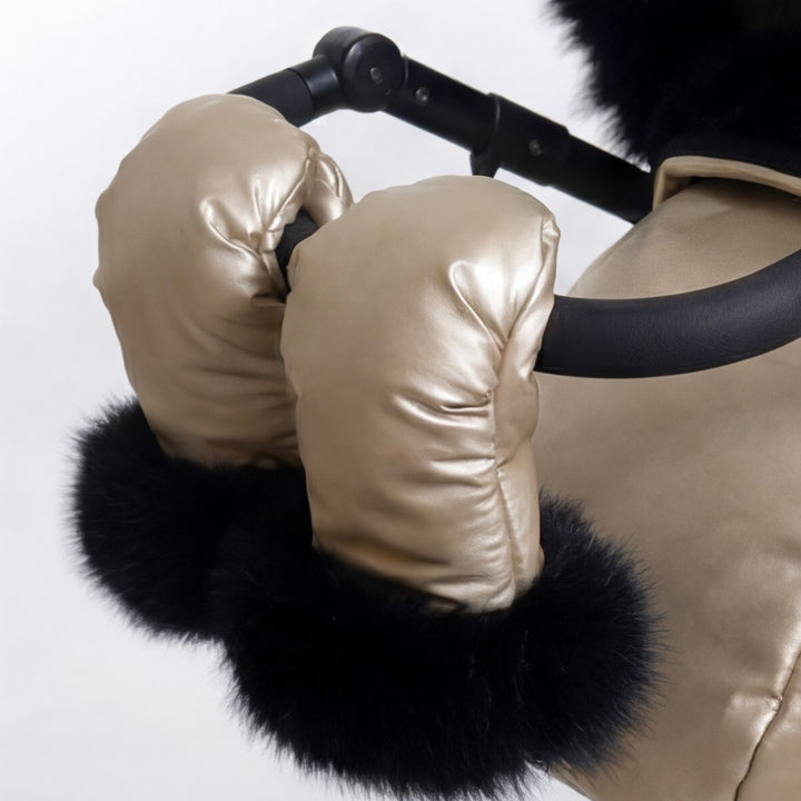 Close-up of a beige stroller cover mittens with black arctic fox fur lining, attached to a stroller handle against a white background.