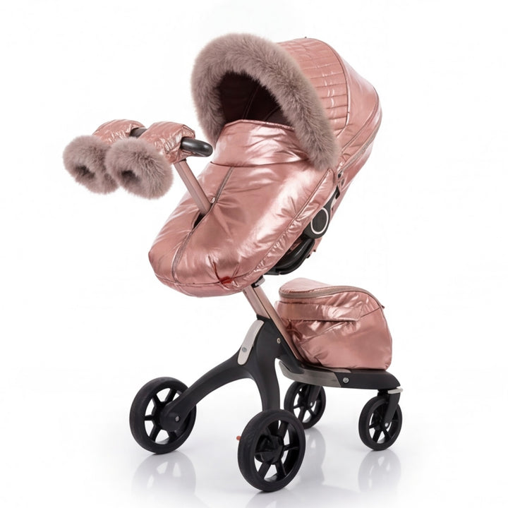 Side view of a rose gold metallic stroller cover set with quilted canopy, beige faux fur trim, matching footmuff, and mittens, displayed on a stroller frame against a white background.