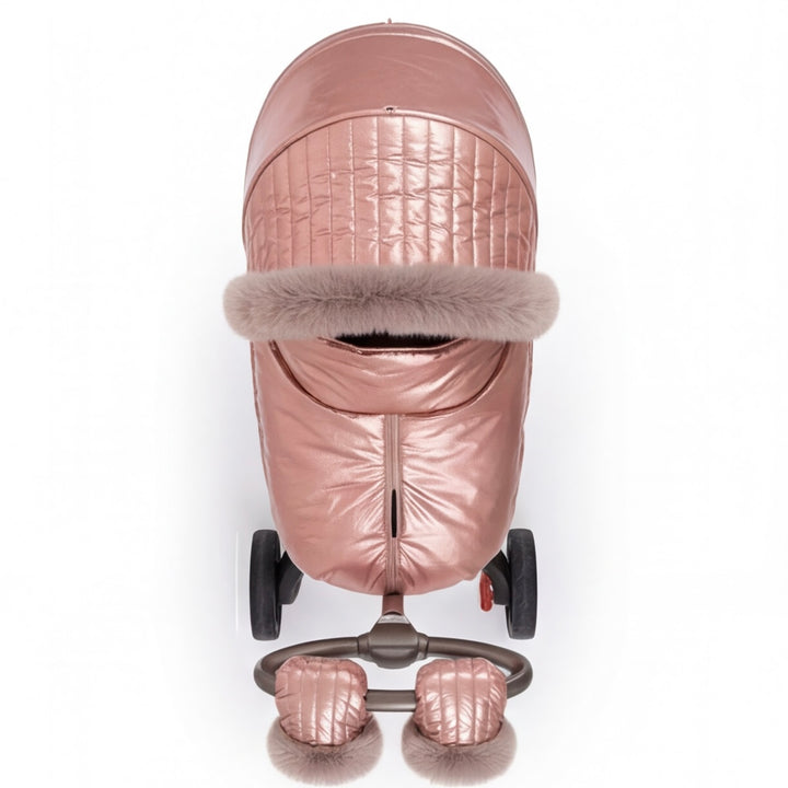 Front view of a rose gold metallic stroller cover with quilted canopy, beige faux fur trim, and matching footmuff, displayed on a stroller frame against a white background.