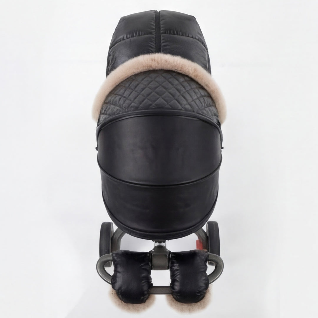 Back view of a black luxury stroller cover with quilted canopy, beige faux fur trim, and matching footmuff, displayed on a stroller frame against a white background.