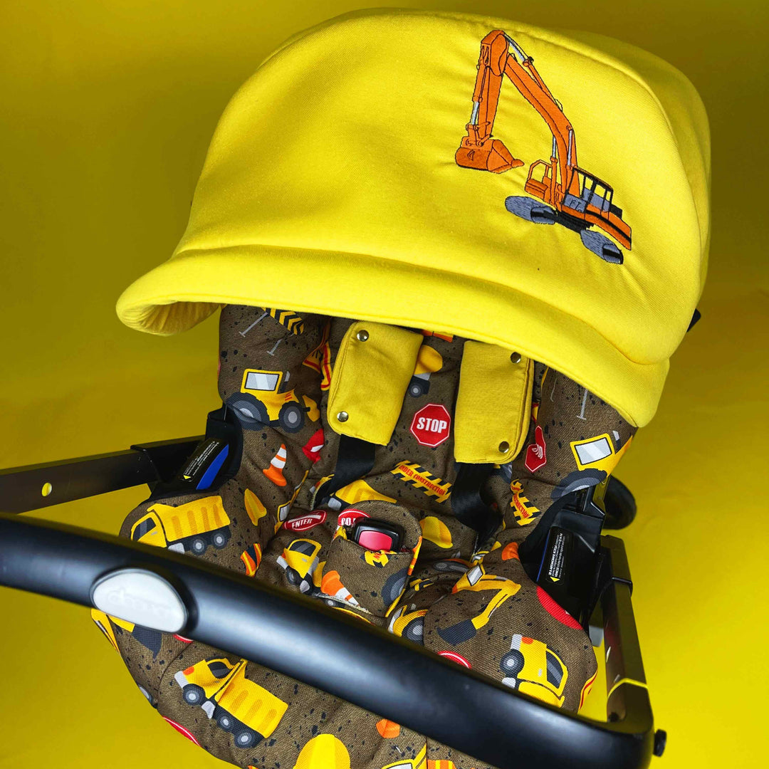 Front view Doona car seat cover with construction vehicle print and yellow canopy embroidered with excavator.