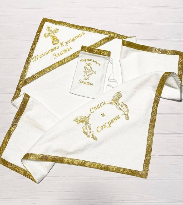 A personalized embroidered baptism blanket laid flat, predominantly white with gold embroidery and lace details, with the name 'Svetlana' embroidered on it.