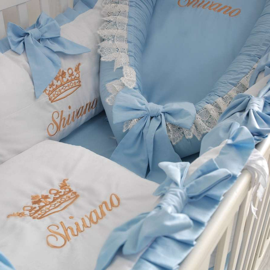 Baby crib with blue and white bedding, featuring the brand 'Shivano'.