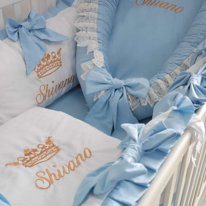 Baby crib with blue and white bedding, featuring the brand 'Shivano'.