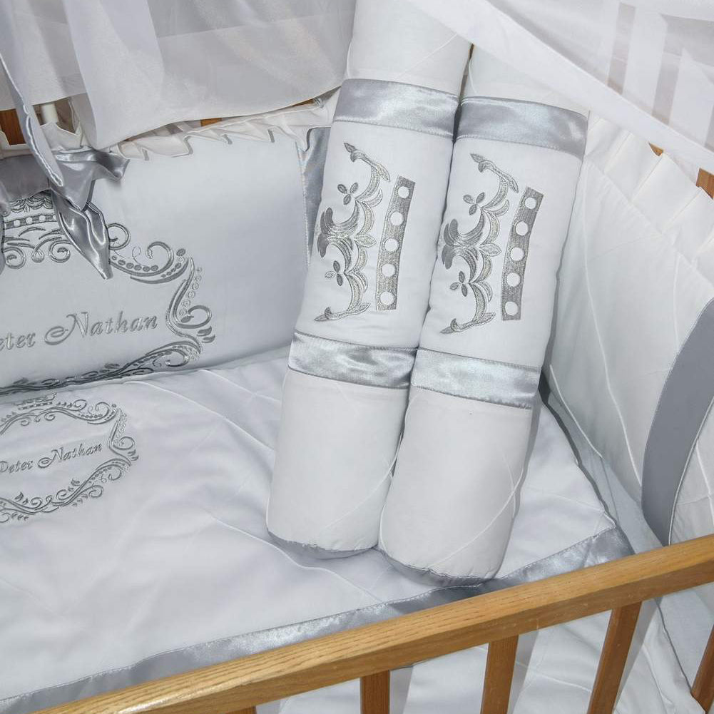 White crib set with silver embroidery on a wooden crib