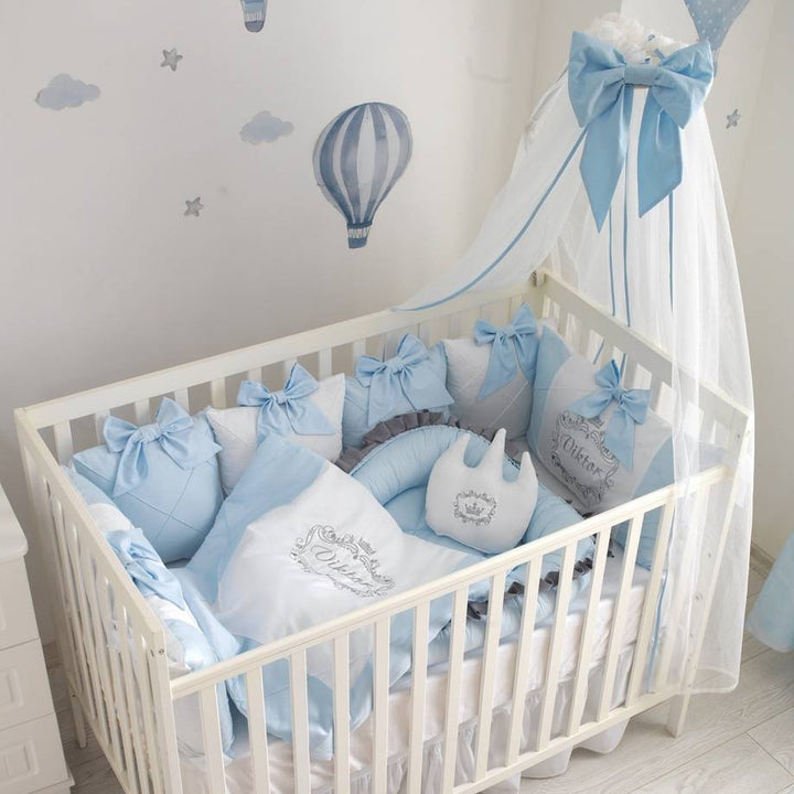 Baby crib with blue and gray bedding and decorative elements in a nursery.