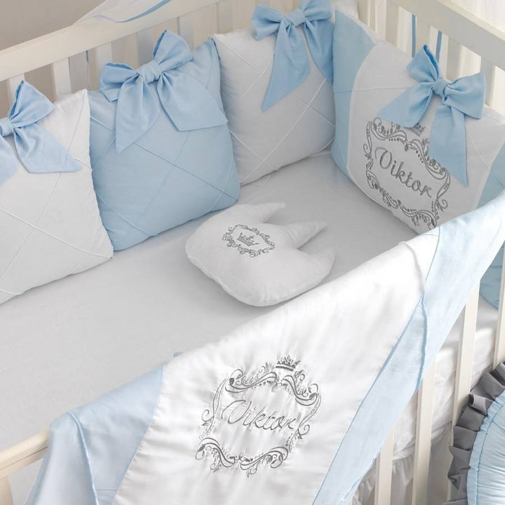 Baby crib with blue and white bedding featuring embroidered names